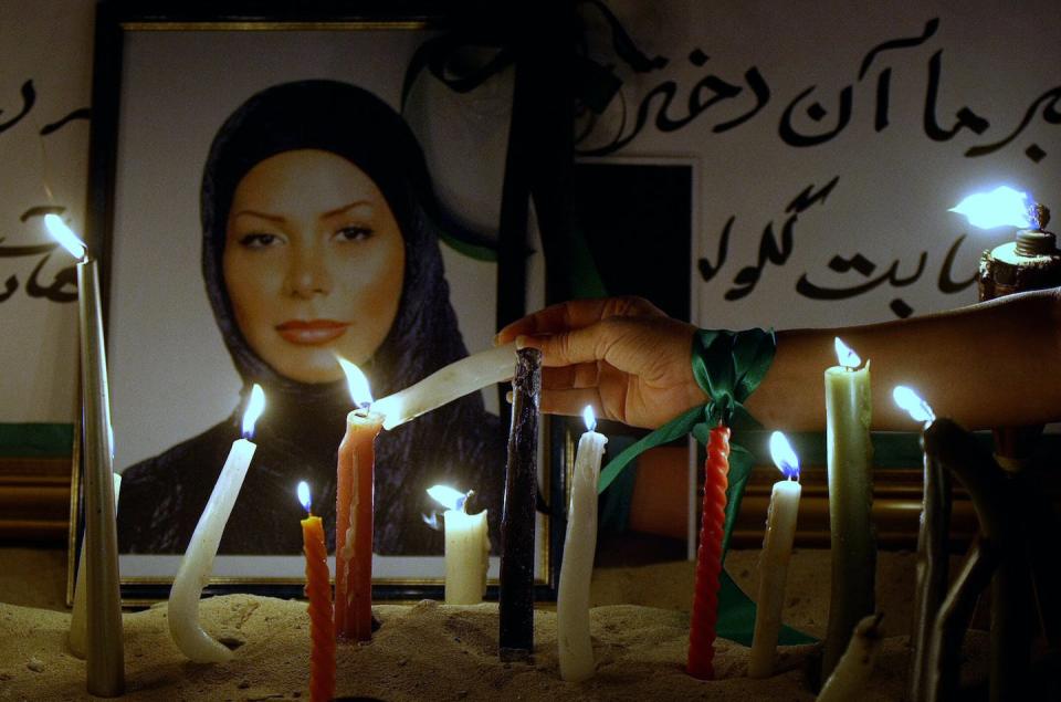 An Iranian sporting a green ribbon on her arm lights a candle in front of a picture of Neda Agha-Soltan, a young Iranian woman who was killed in 2009. <a href="https://www.gettyimages.com/detail/news-photo/an-iranian-sporting-a-green-ribbon-on-her-arm-lights-a-news-photo/88693049?adppopup=true" rel="nofollow noopener" target="_blank" data-ylk="slk:Marwan Naamani/AFP via Getty Images;elm:context_link;itc:0;sec:content-canvas" class="link ">Marwan Naamani/AFP via Getty Images</a>