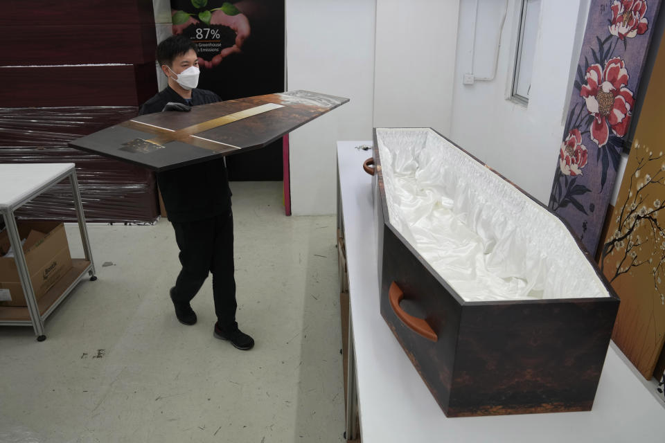 A worker places a cover on top of a paper coffin at the factory of LifeArt in Hong Kong, Friday, March 18, 2022. Hong Kong is running short of coffins during its deadliest outbreak of the coronavirus pandemic. LifeArt, a company in Hong Kong is trying to make an alternative, cardboard coffin, which it says is environmentally-friendly. (AP Photo/Kin Cheung)