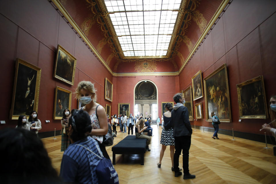 Visitors watch pantings at the Louvre Museum, in Paris, Monday, July 6, 2020. The home of the world's most famous portrait, the Louvre Museum in Paris, reopened Monday after a four-month coronavirus lockdown. (AP Photo/ Thibault Camus)