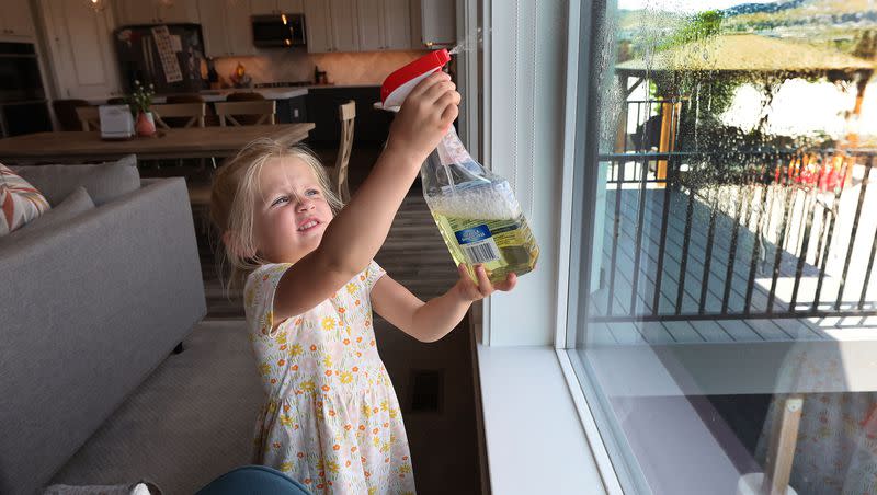 Ruby Evanson, 5, cleans windows at home in Lehi on Thursday, May 18, 2023.