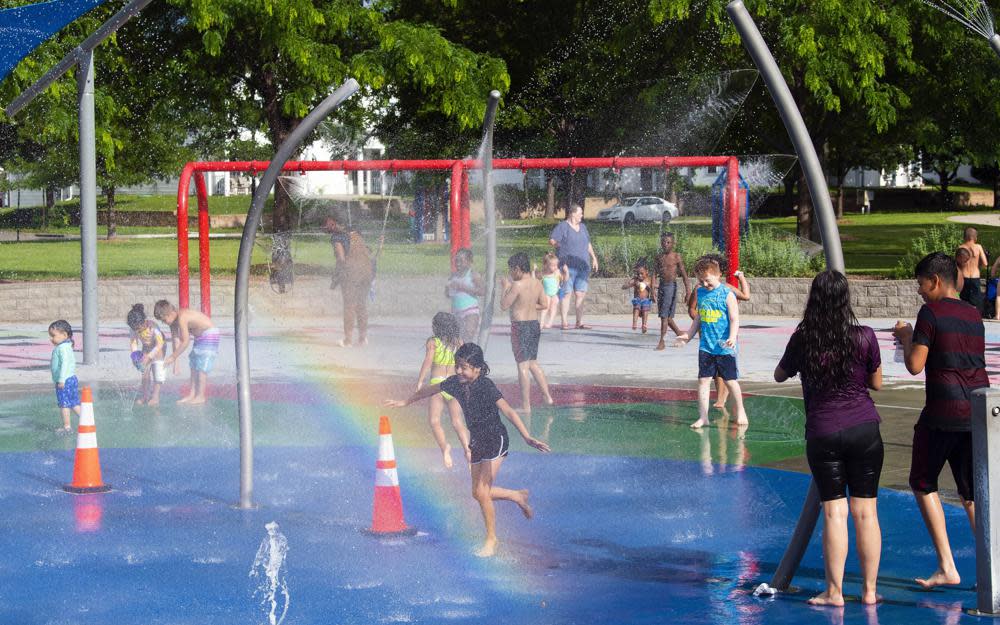 FILE – Children and adults take advantage of the warm weather to cool off at the Trago Spray Park on Friday, June 10, 2022, in Lincoln, Neb. The fast-changing coronavirus has kicked off summer in the U.S. with lots of infections but relatively few deaths compared to its prior incarnations. COVID-19 is still killing hundreds of Americans each day, but for many people the virus is not nearly as dangerous as it was. (Kenneth Ferriera/Lincoln Journal Star via AP)