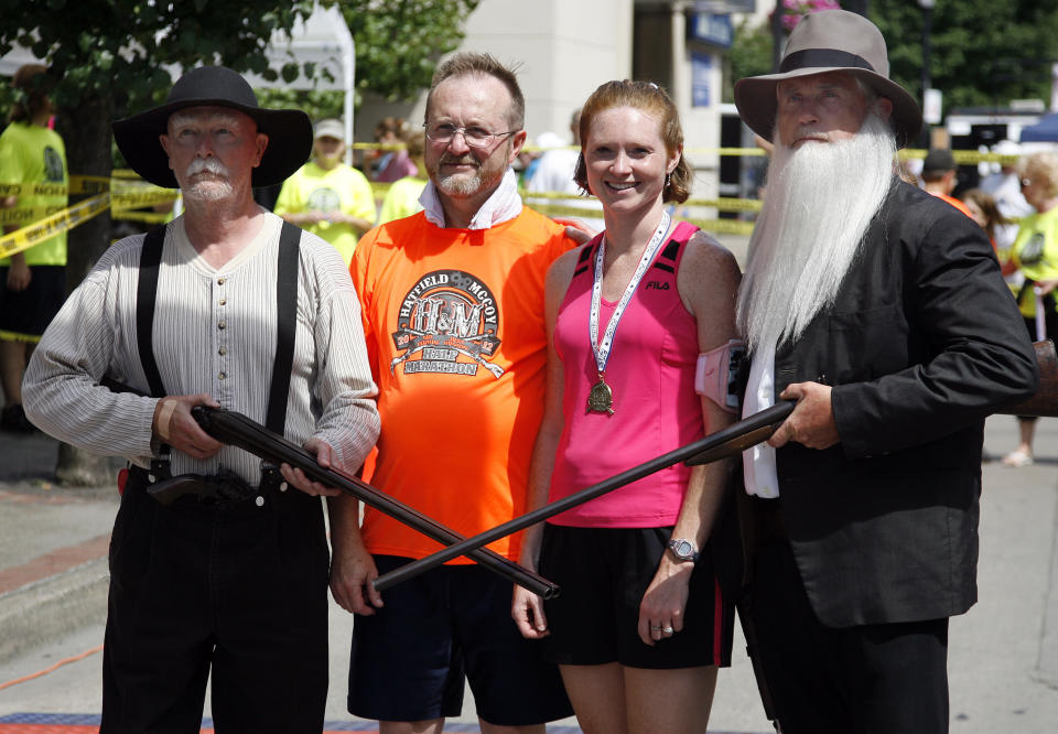 In a Saturday, June 9, 2012 photo, Doyle Van Meter, left, dressed as Randall McCoy and Jerry Akers, right, as Devil Anse Hatfield pose with runners after they finish the Hatfield-McCoy Marathon in Williamson, W.V. (AP Photo/ James Crisp)