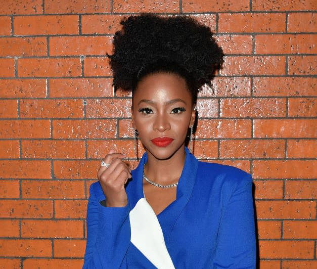 Teyonah standing in front of a brick-pattern wall