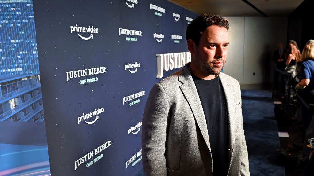 scooter braun looking offscreen at photographers in front of a backdrop