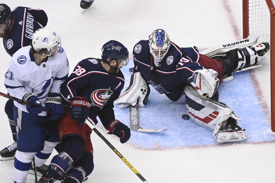 Columbus Blue Jackets goaltender Joonas Korpisalo (70) makes a stop as Tampa Bay Lightning center Brayden Point (21) and Blue Jackets center Boone Jenner (38) look for a rebound during the third period of Game 3 of an NHL hockey first-round playoff series, Saturday, Aug. 15, 2020, in Toronto. (Nathan Denette/The Canadian Press via AP)