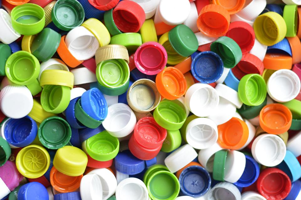 Viele verschiedenfarbige Plastikdeckel liegen auf einem Haufen.