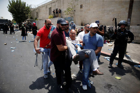 Palestinians carry a person during clashes with Israeli security forces outside Jerusalem's Old city July 21, 2017. REUTERS/Ronen Zvulun