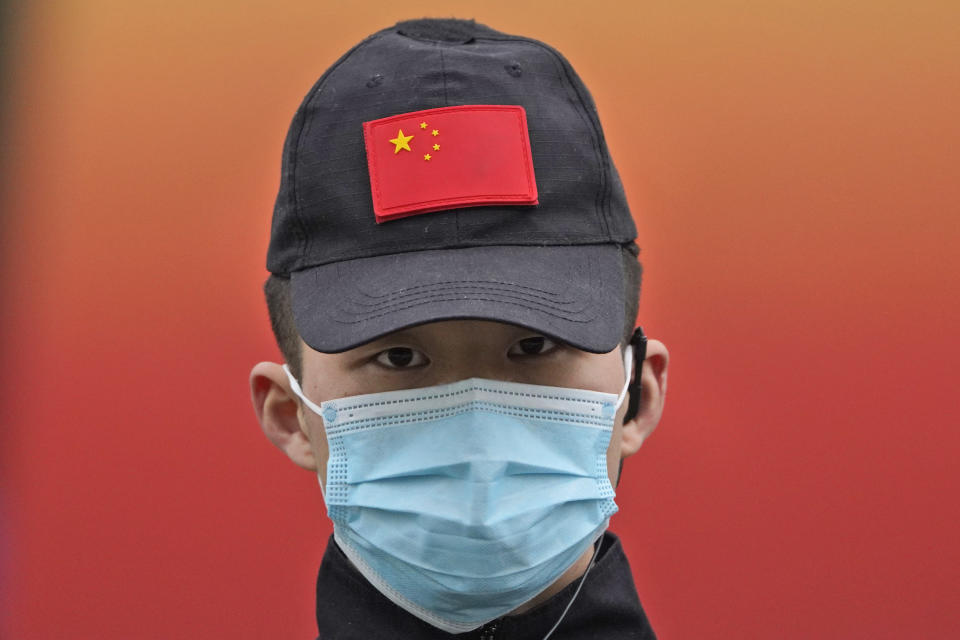 A security officer wearing a mask and a cap with the Chinese national flag guards the entrance after the World Health Organization team arrive at an exhibition about the fight against the coronavirus in Wuhan in central China's Hubei province on Saturday, Jan. 30, 2021. The World Health Organization team investigating the origins of the coronavirus pandemic visited another Wuhan hospital that had treated early COVID-19 patients on their second full day of work on Saturday. (AP Photo/Ng Han Guan)