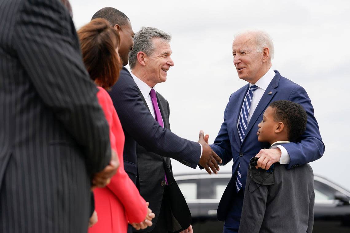 President Joe Biden shakes hands with Environmental Protection Agency Administrator Michael Regan as Regan’s son Matthew, 7, stands with Biden at Piedmont Triad International Airport, in Greensboro, N.C., Thursday, April 14, 2022. North Carolina Gov. Roy Cooper looks on at center.