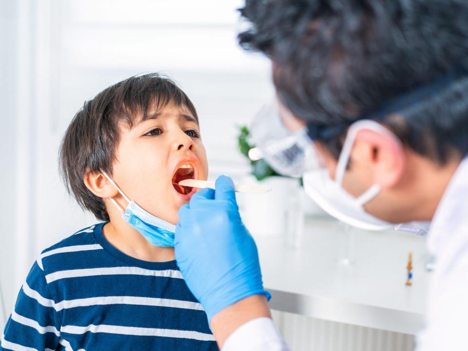 little boy examined for strep throat by doctor at office