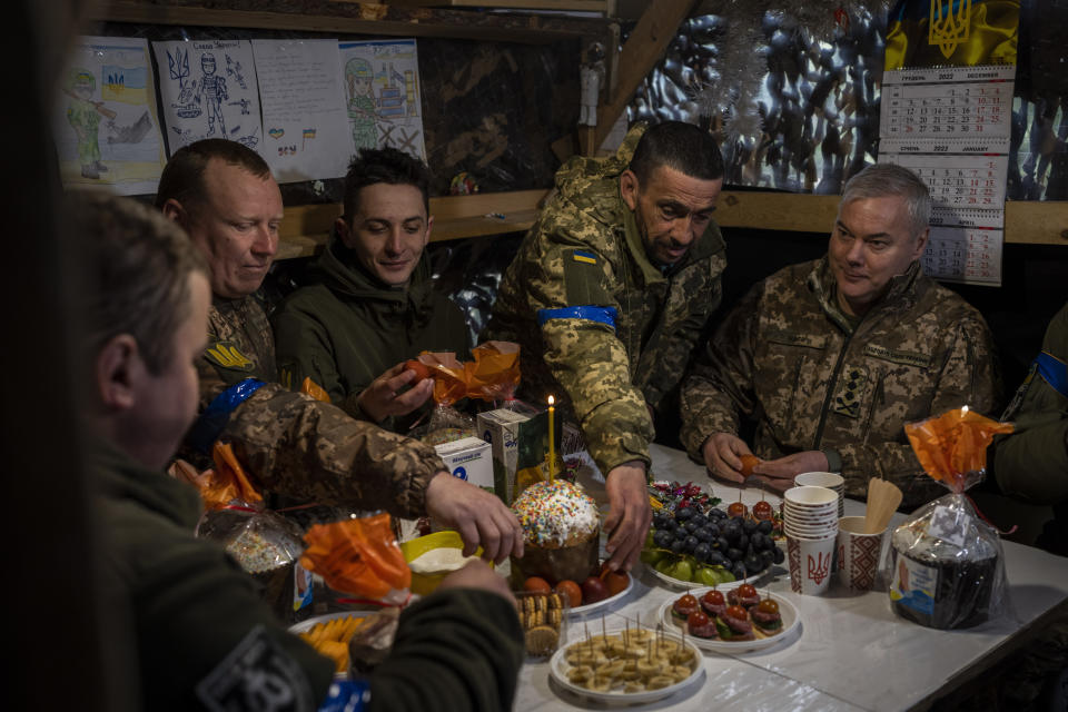 Lieutenant General Serhiy Nayev, Commander of the Joint Forces of the Ukrainian Armed Forces, right, joins an Easter meal with Ukrainian servicemen stationed in a defensive post in Kyiv region, Saturday, April 15, 2023. (AP Photo/Bernat Armangue)