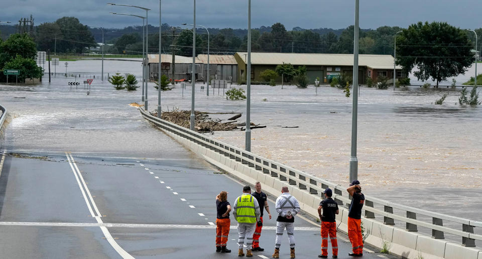 State emergency staff stand near the entrance to the flooded Windsor bridge on the outskirts of Sydney, Australia, Thursday, March 3, 2022. Around 500,000 people in Sydney and its surrounds have been told to evacuate or prepare to flee floodwaters as torrential rain lashes an extraordinarily long stretch of the Australian east coast. (AP Photo/Rick Rycroft)