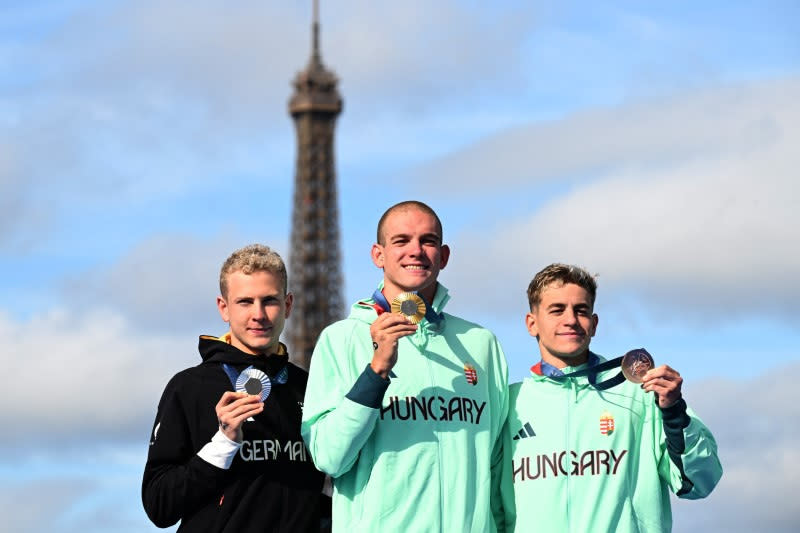 Juegos Olímpicos de París 2024 - Natación de maratón - Ceremonia de victoria de los 10 km masculinos - Puente Alejandro III, París, Francia - 09 de agosto de 2024. El medallista de oro Kristof Rasovszky de Hungría celebra con su medalla mientras posa para una fotografía junto al medallista de plata Oliver Klemet de Alemania y el medallista de bronce David Betlehem de Hungría REUTERS/Angelika Warmuth