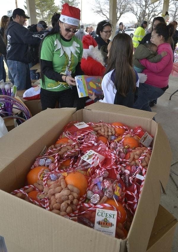 Volunteers distribute Christmas stockings and presents at the 11th annual Mary 'Mama' Jaramillo Christmas Stocking Giveaway at St. Anne's Park in 2015. [CHIEFTAIN PHOTO/FILE]