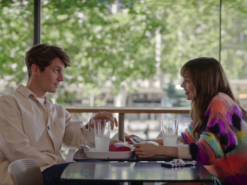 gabriel the french chef sitting across the table from emily cooper in emily in paris  season 3