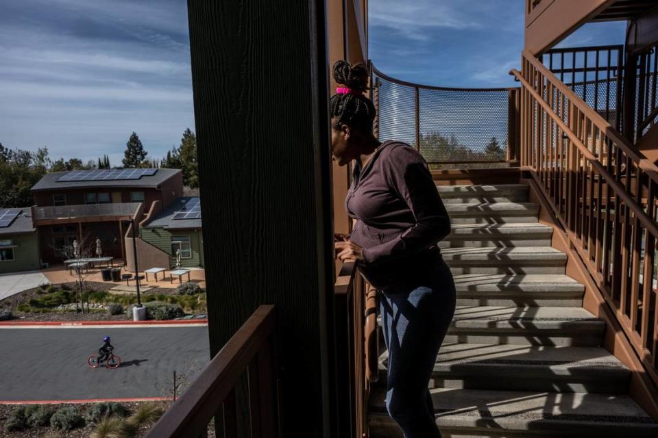 From the balcony of her low-income apartment, Yolo Basic Income program recipient Marquisha Brown watches her son Elijah bicycle on April 5, 2023, while her boyfriend, not pictured, supervises him below. Brown said she loves the community where she lives now. “I think stability is him feeling safe and secure, and this is his home,” Brown said.