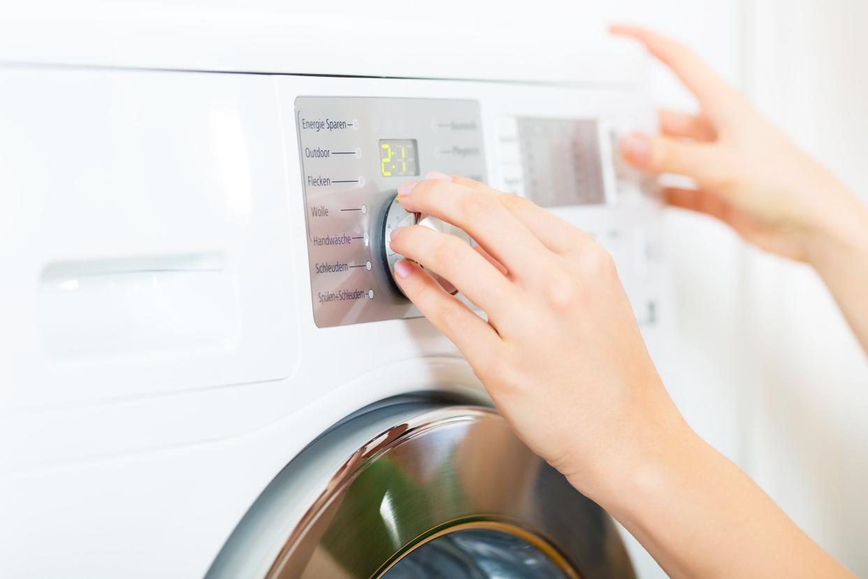 woman using a laundry day at home, selecting the setting