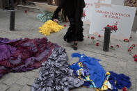 A flamenco dancer dances between flamenco dresses and roses on the ground outside the Villa Rosa Tablao flamenco venue during a protest in Madrid, Spain, Thursday March 4, 2021. The National Association of Tablaos protested outside the mythical Villa Rosa Tablao which has been forced to close permanently due to the covid pandemic. (AP Photo/Paul White)