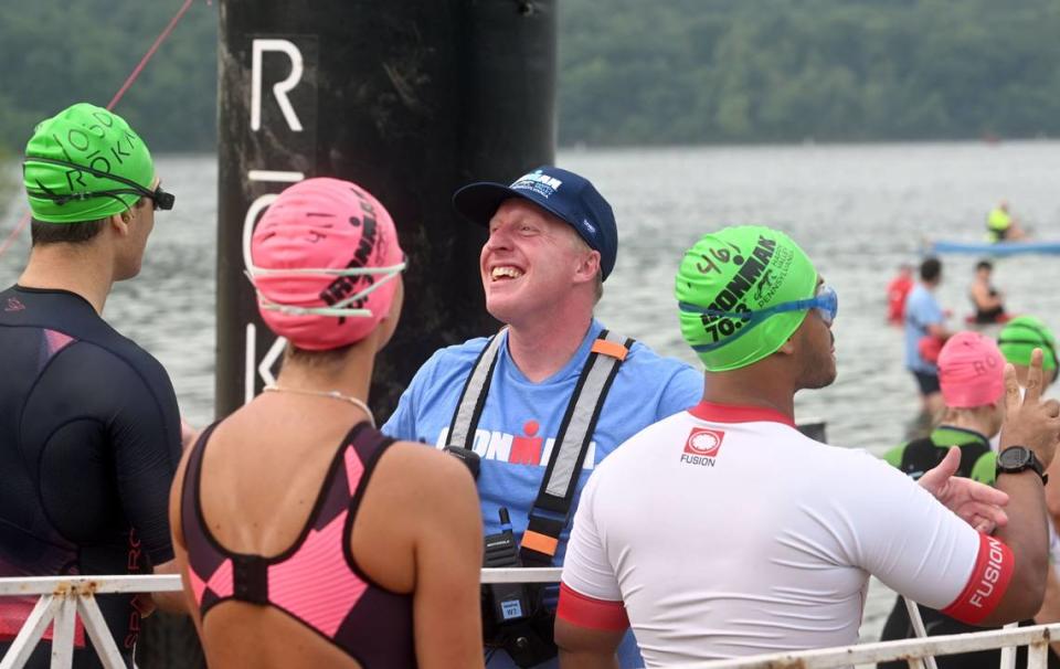 Ironman 70.3 Pennsylvania Happy Valley race director Josh Cone laughs with athletes as he lets them enter the water for the 1.2 mile swim in Foster Joseph Sayers Lake at Bald Eagle State Park on Sunday, June 30, 2024.