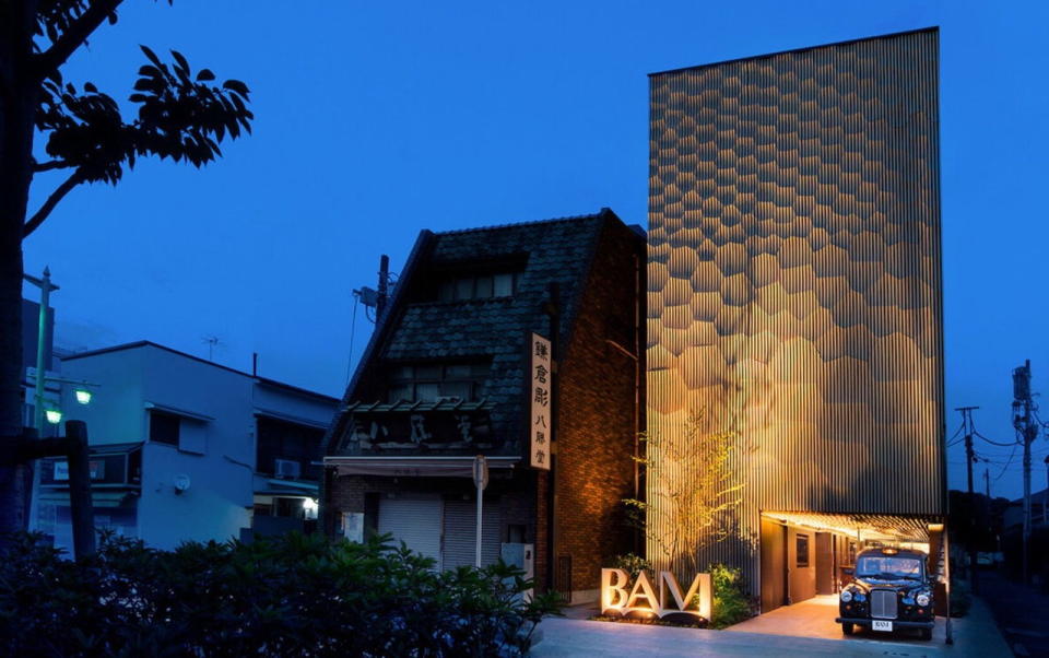 Nighttime view of Kengo Kuma's rippling wood facade for the British Antique Museum in Kamakura, Japan.