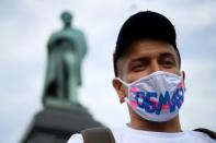 A man protesting against the changes wears a facemask emblazoned with the word "Deception"