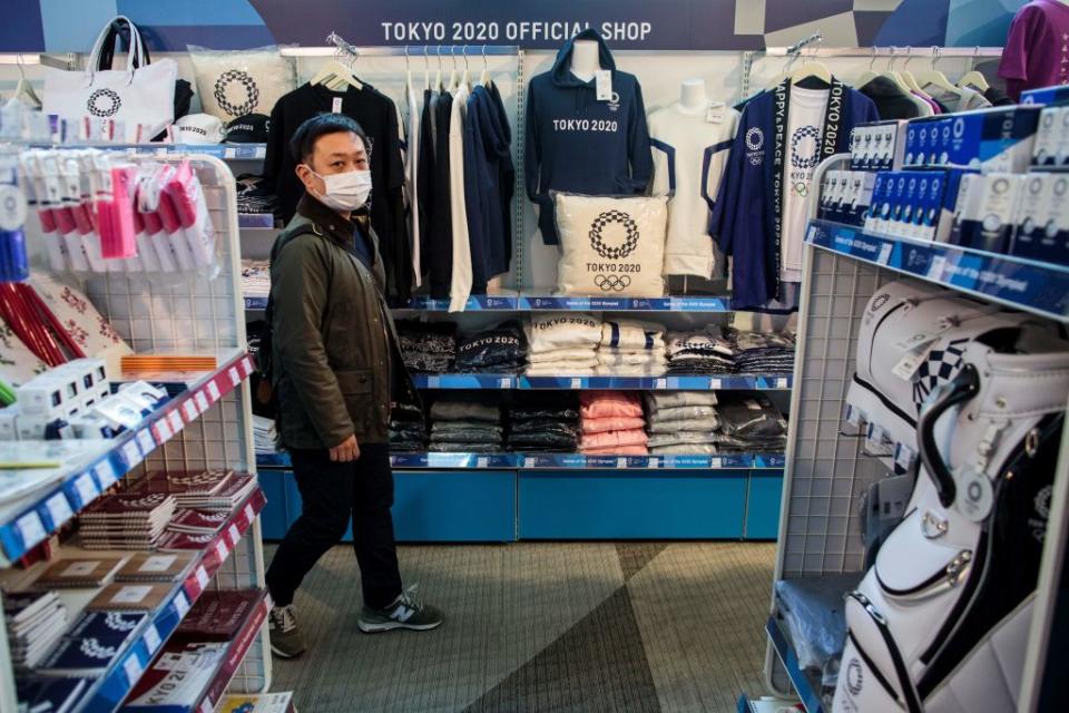 A man wearing a face mask, amid concerns over the spread of the COVID-19 novel coronavirus, visits a Tokyo 2020 official shop in Tokyo on March 25, 2020, the day after the historic decision to postpone the 2020 Tokyo Olympic Games. | Behrouz Mehri–AFP/Getty Images