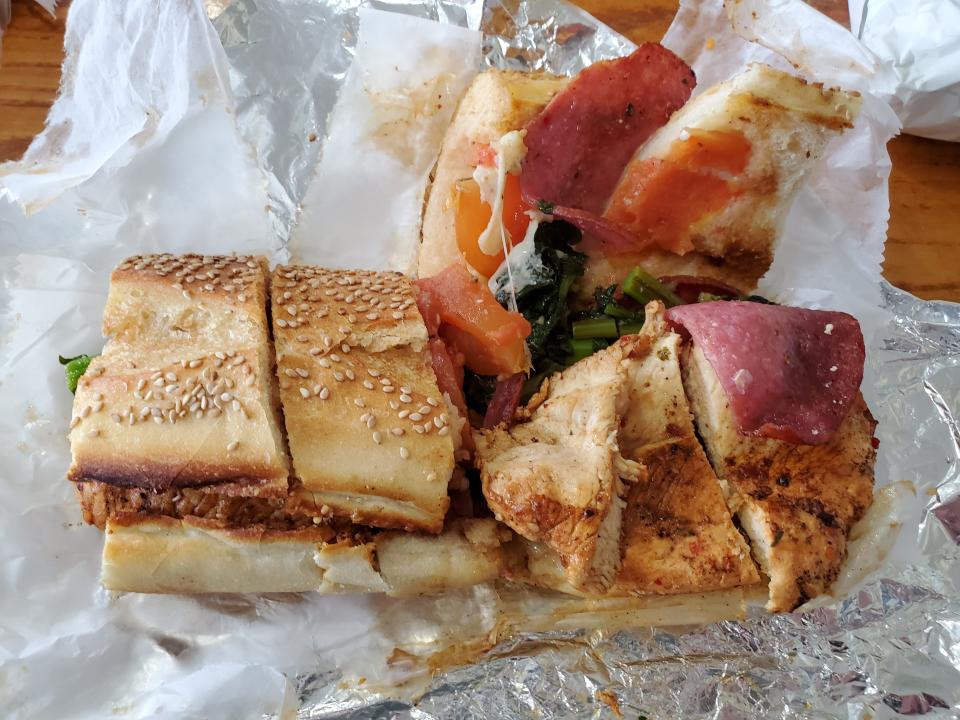 A peek inside the Diavlo sandwich, which features spicy seasoned grilled chicken breast with salami, tomatoes, cheddar herb spread and broccoli rabe.
