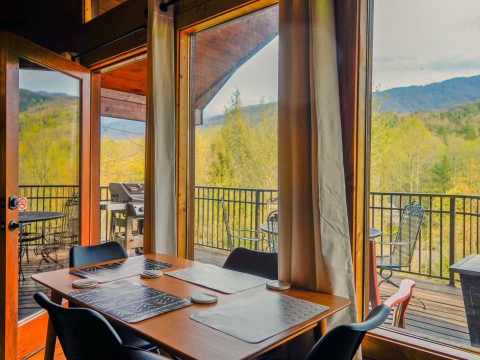 A table with four chairs against a window with views of the mountains.