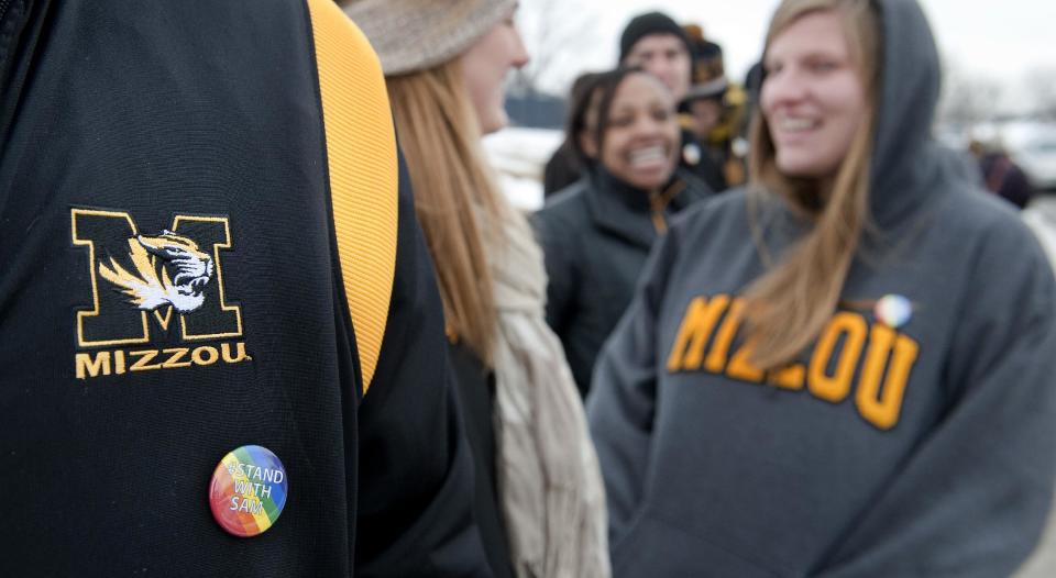 Drew Carlton wears a #Stand With Sam button as he joins several hundred supporters of Michael Sam stand along Stadium Boulevard across the street from Memorial Stadium Saturday, Feb. 15, 2014, in Columbia, Mo. (AP Photo/L.G. Patterson)