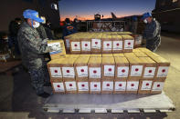 Members of Japan's Air Self-Defense Force help load boxes of emergency relief goods into an airplane at an airbase in Komaki, central Japan, Thursday, Jan. 20, 2022, as they were preparing to take off for Australia on their way to Tonga to transport the relief goods, following Saturday's volcanic eruption near the Pacific nation. Japan's Defense Ministry said it would send emergency relief, including drinking water and equipment for cleaning away volcanic ash. (Kyodo News via AP)