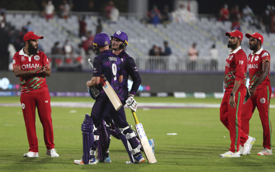 Scotland's batsman Richie Berrington, middle facing camera, with teammate Matthew Cross celebrates after scoring winning runs at the end of the Cricket Twenty20 World Cup first round match between Oman and Scotland in Muscat, Oman, Thursday, Oct. 21, 2021. Scotland beat Oman by 8 wickets with 18 balls remaining. (AP Photo/Kamran Jebreili)