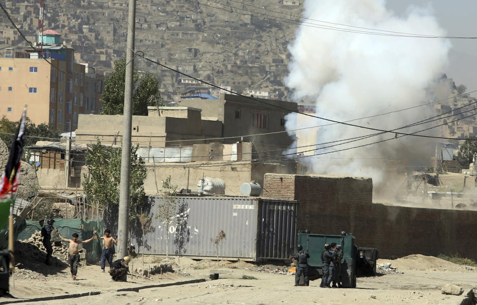 Smoke rises from a house where suspected attackers were hiding while policemen arrests two suspects, left, in Kabul, Afghanistan, Tuesday, Aug. 21, 2018. The Taliban fired rockets toward the presidential palace in Kabul Tuesday as President Ashraf Ghani was giving his holiday message for the Muslim celebrations of Eid al-Adha, said police official Jan Agha. (AP Photo/Rahmat Gul)