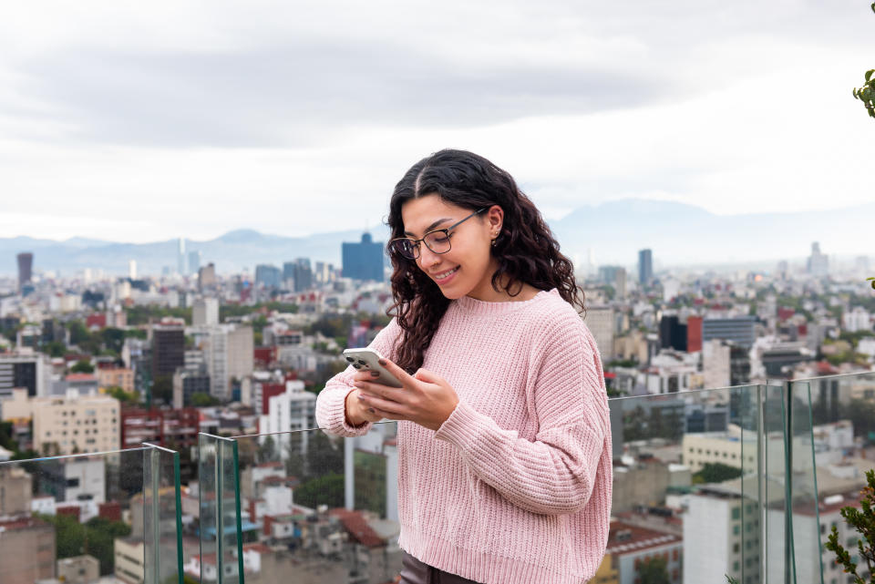 Una joven usa su teléfono inteligente en una terraza de Ciudad de Mexico. (Foto: Getty)