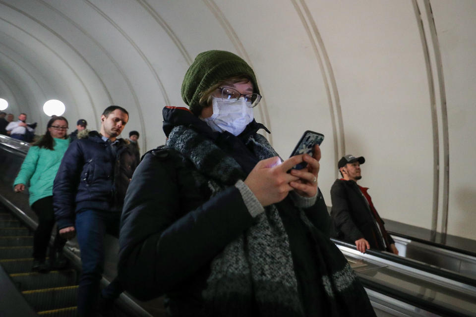 A woman wears a face mask while using her cellphone as she enters a Moscow Underground station during the coronavirus pandemic. (Photo: Mikhail Tereshchenko via Getty Images)