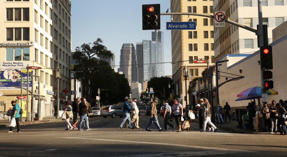 People cross a city street with skyscrapers in the background