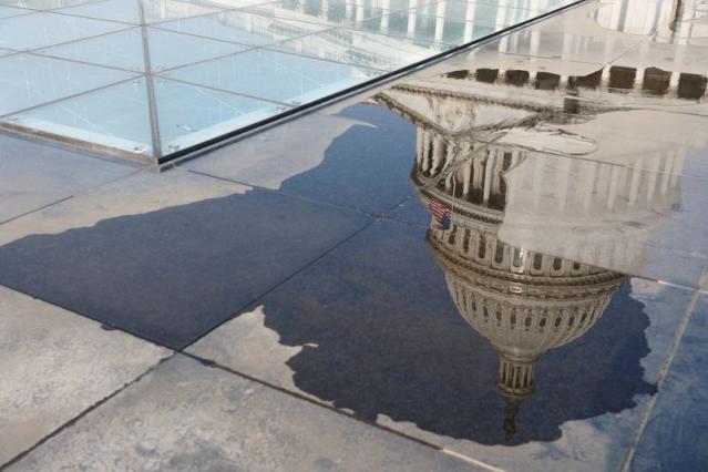 The U.S. Capitol is reflected in a puddle in Washington