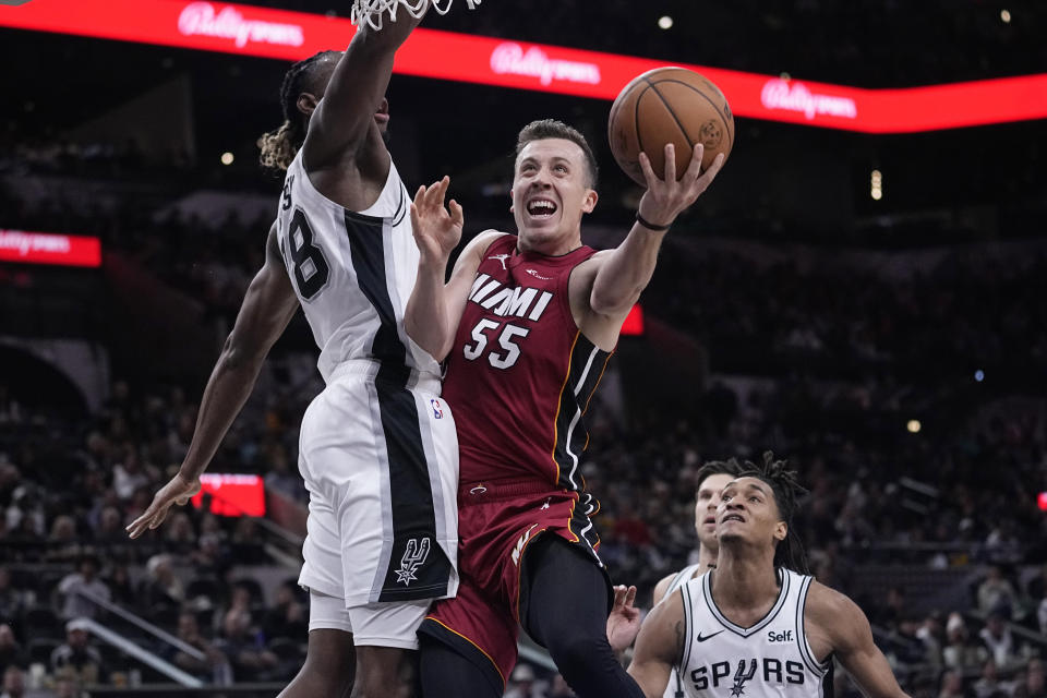 Miami Heat forward Duncan Robinson (55) drives to the basket against San Antonio Spurs center Charles Bassey (28) during the first half of an NBA basketball game in San Antonio, Sunday, Nov. 12, 2023. (AP Photo/Eric Gay)