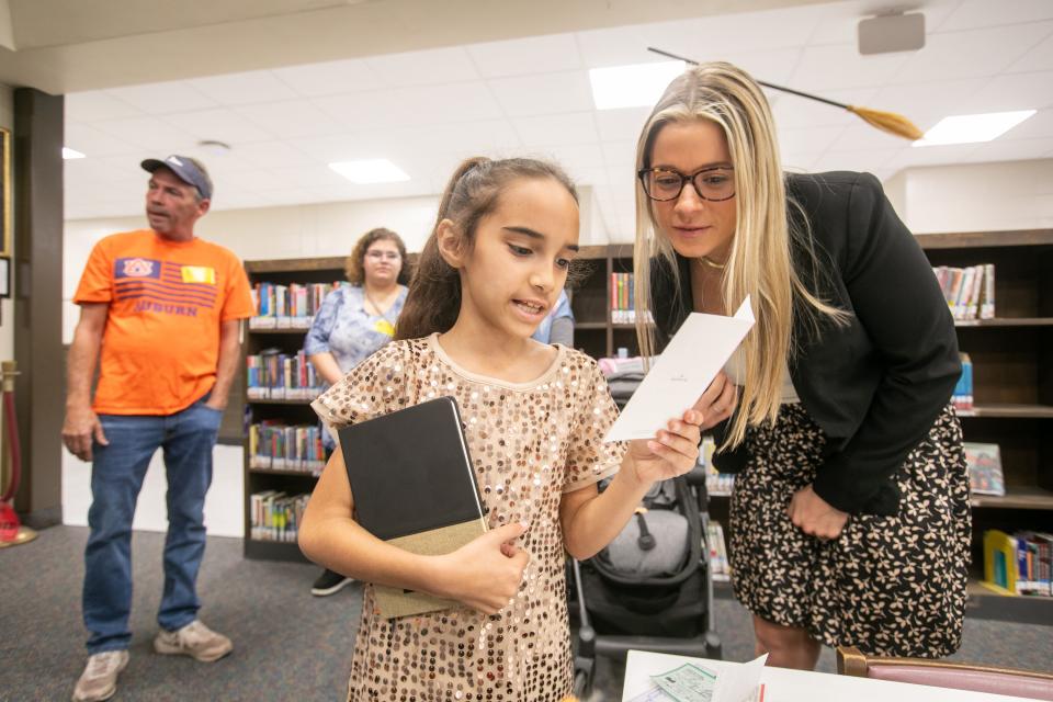 Shayla Reeves, 9, reads the card with Sarah James after she is awarded the funds to go to the University of Miami to participate in their National Youth Leadership Forum.