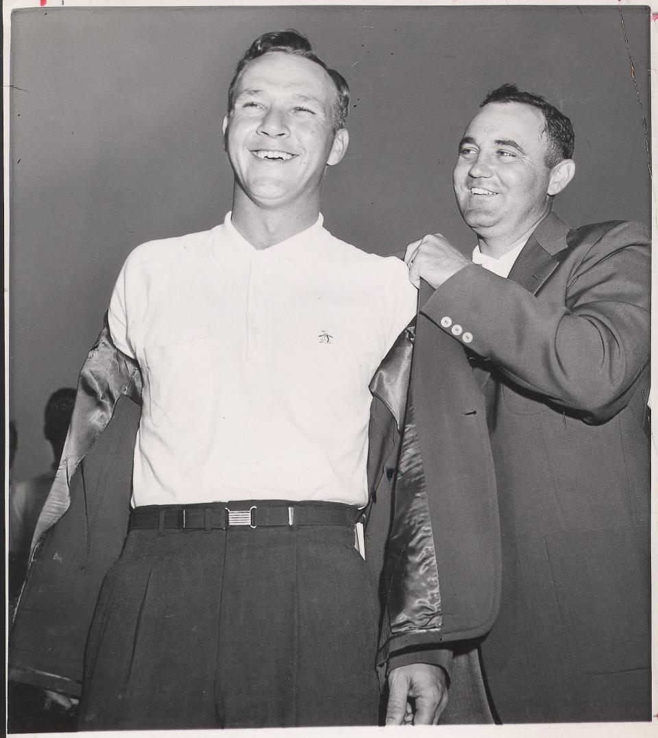 Arnold Palmer gets his first green jacket, with help from Doug Ford.