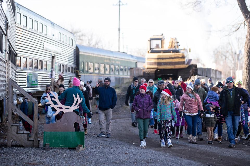 Passengers walk into the yard of the Steam Railroading Institute before the North Pole Express takes off in Owosso on Friday, Nov. 24, 2023.