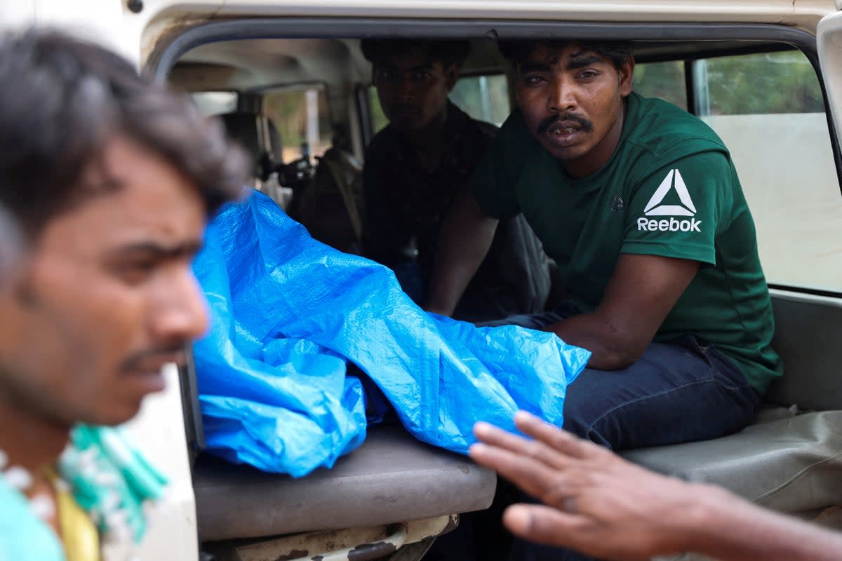 Mohammad Imam Ul Haq’s relatives bid farewell to other family members before an ambulance leaves with a makeshift coffin carrying his nephew (REUTERS)