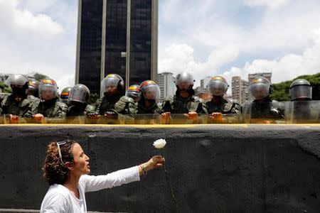 A demonstrator holds up a flower in front of riot policemen during a women's march to protest against President Nicolas Maduro's government in Caracas, Venezuela, May 6, 2017. REUTERS/Carlos Garcia Rawlins