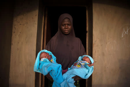 A Muslim woman carries her four-day-old male twins wrapped in blue towels outside the door of her home in Igbo Ora, Oyo State, Nigeria April 3, 2019. REUTERS/Afolabi Sotunde