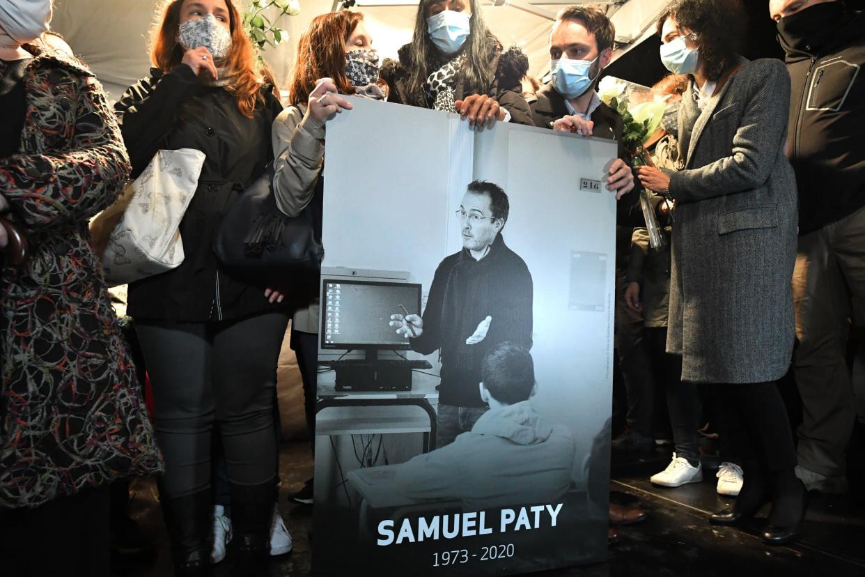 Des participants à la marche blanche en hommage à Samuel Paty portant une photo du professeur.  - Bertrand Guay
