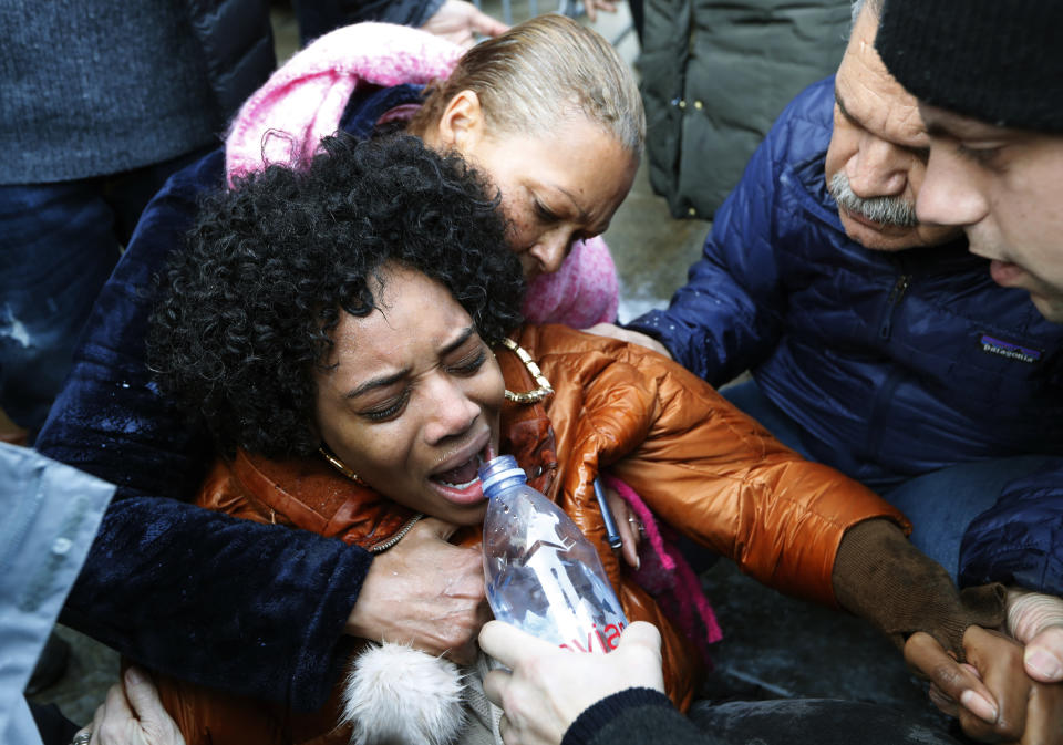 Yandy Smith is helped by others after she was sprayed with pepper spray after she and others stormed the main entrance to the Metropolitan Detention Center, a federal prison where prisoners have gone without heat, hot water and flushing toilets due to an electrical outage, Sunday, Feb. 3, 2019, in the Brooklyn borough of New York. (AP Photo/Kathy Willens)