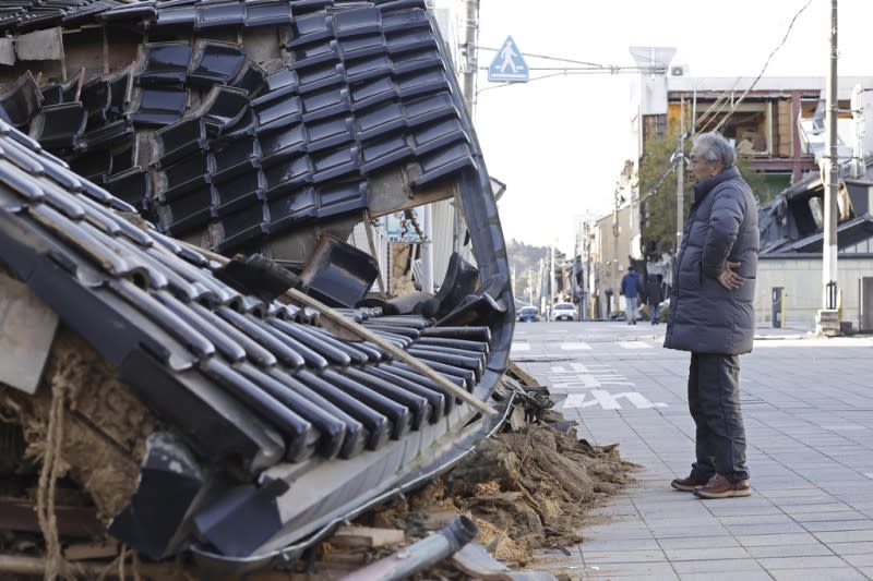 <cite>2024年1月2日，日本石川縣地震後，一名男子站在一家被毀壞的商店前。（AP）</cite>