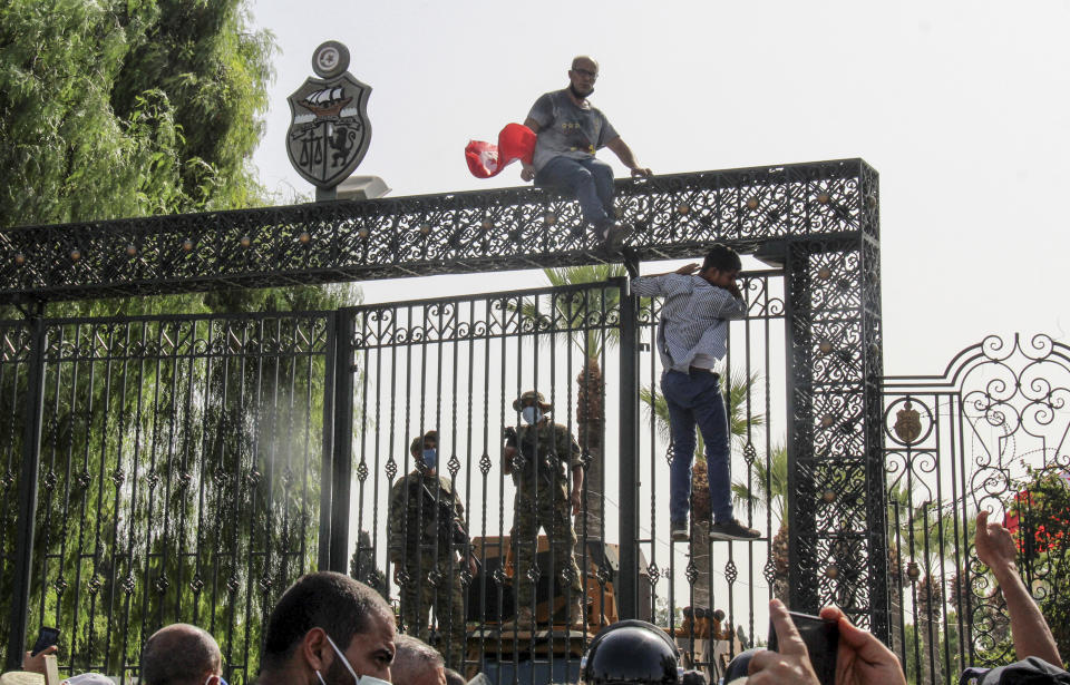 FILE - Tunisian soldiers guard the main entrance of the parliament as demonstrators gather outside the the gate in Tunis, Tunisia, Monday, July 26, 2021. Despite an election debacle, Tunisia's increasingly authoritarian president appears determined to upend the country's political system, threatening to unravel the fragile democracy and collapse the economy in the North African nation that a decade ago stood out as a model of good governance and economic prosperity in the aftermath of the Arab Spring protests. (AP Photo/Hedi Azouz, File)