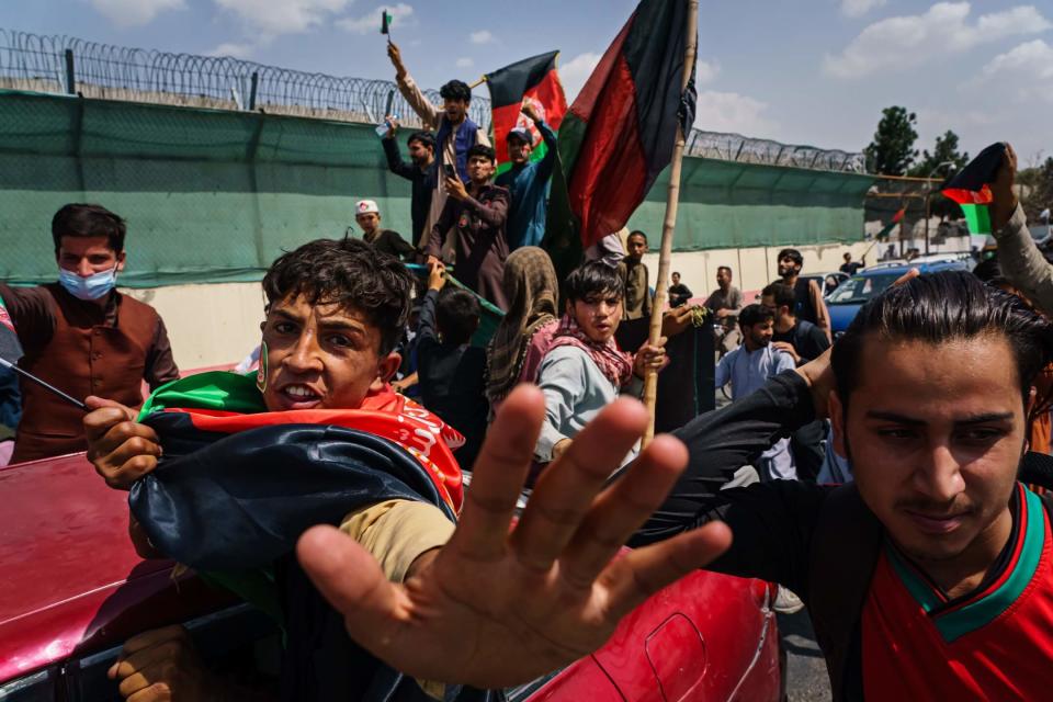 2021年8月19日，阿富汗首都喀布爾，手持橫額及揮動阿富汗伊斯蘭共和國國旗的阿富汗人民，無懼塔利班入侵，在市中心聚集示威。
