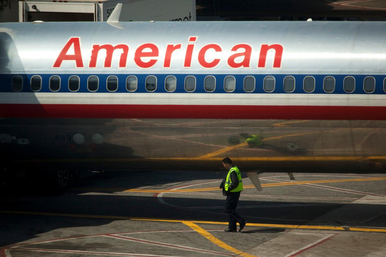 An airport worker walks past an American Airlines Inc. plane standing at a gate at LaGuardia Airport in the Queens borough of New York, U.S., on Monday, April 25, 2011. American Airlines Inc. is trying to grab market share in New York, the biggest and possibly most-contested U.S. aviation market, with terminal upgrades at LaGuardia Airport. Delta Air Lines Inc.'s bid to redo its space remains in limbo, bogged down in talks with federal regulators and US Airways Group Inc. about access to more landing rights. Photographer: Michael Nagle/Bloomberg (Bloomberg)