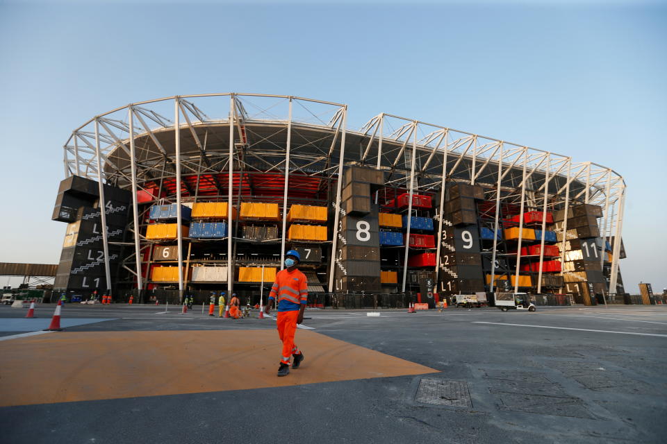 A worker walks in front of Ras Abu Aboud Stadium, one of the venues of the Qatar World Cup 2022. 